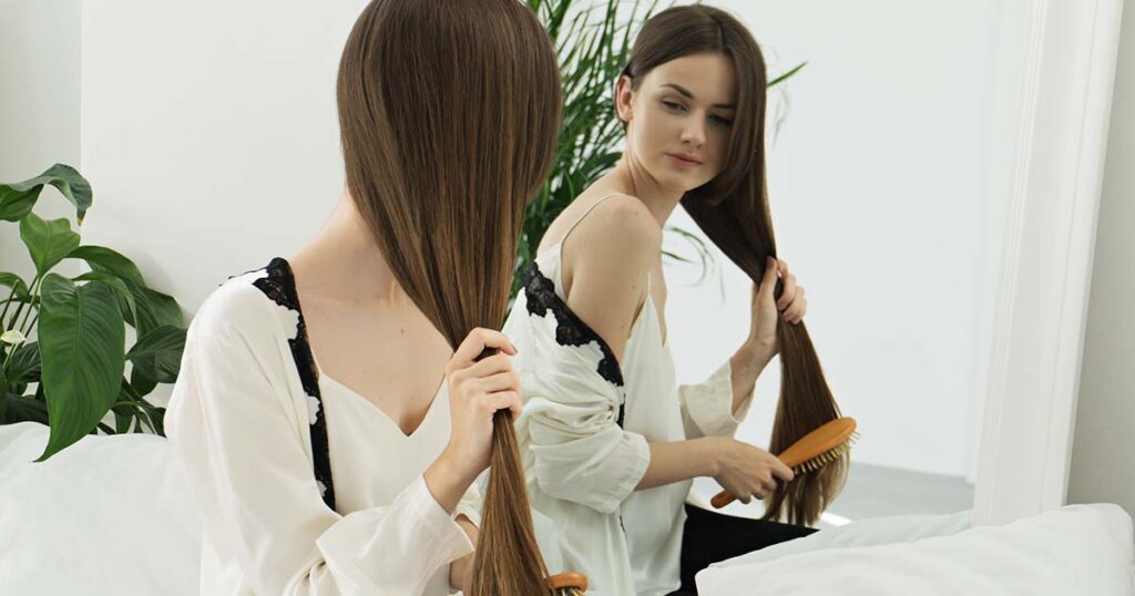 image of attractive girl combing long hair at home