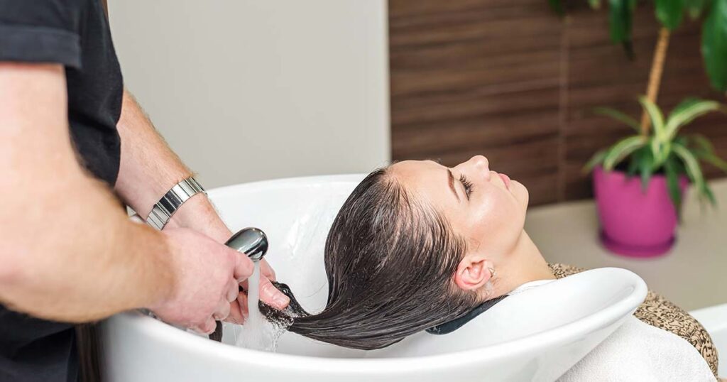 Haidresser washing woman's hair.